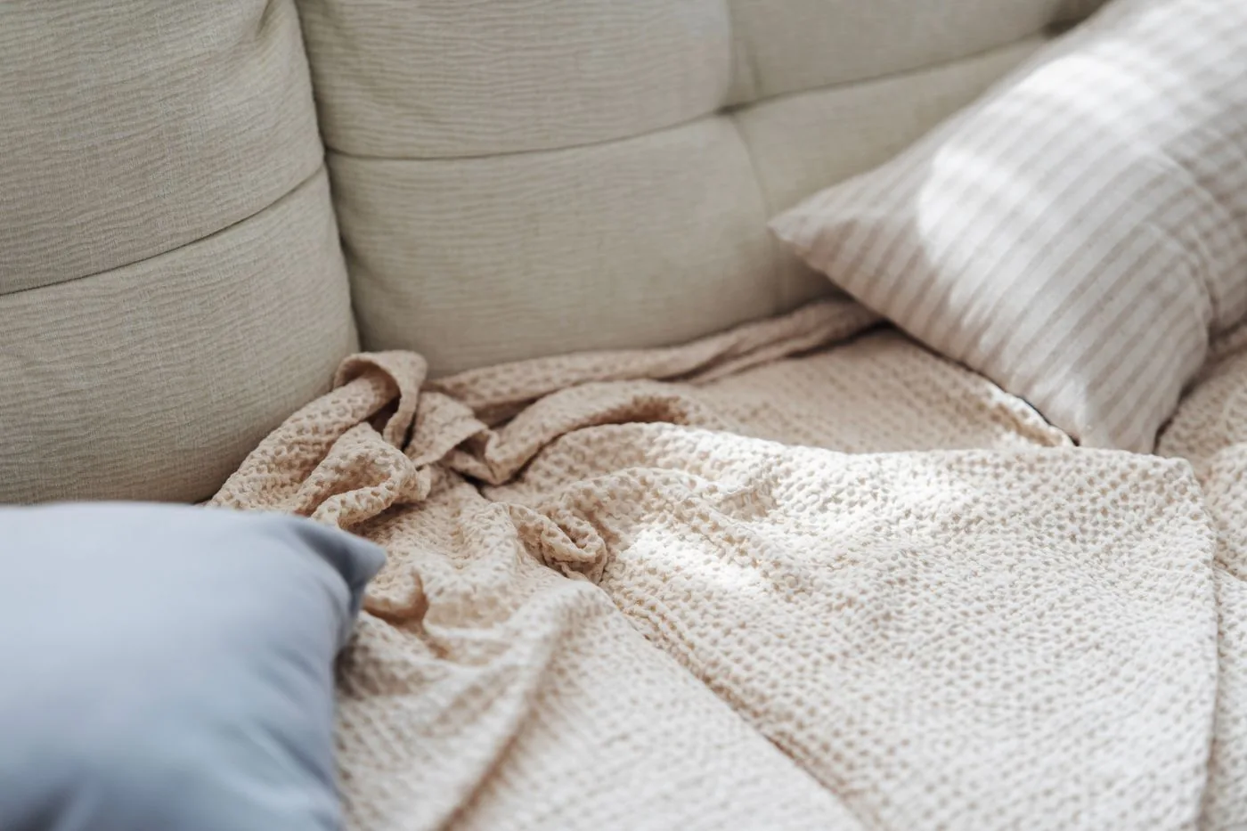 Beige sofa with soft pillows and a textured blanket
