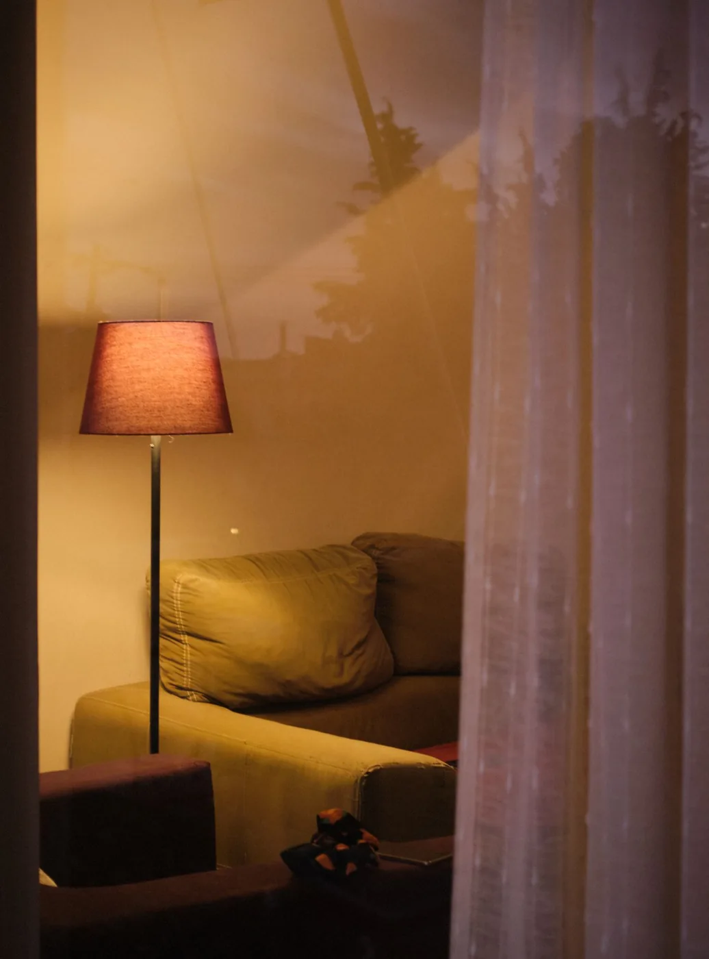 Warm floor lamp beside a sofa and sheer curtains