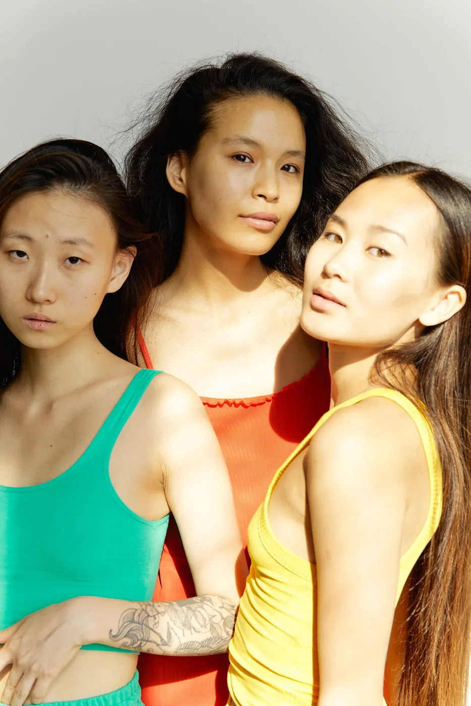 Three women wearing colorful tank tops together