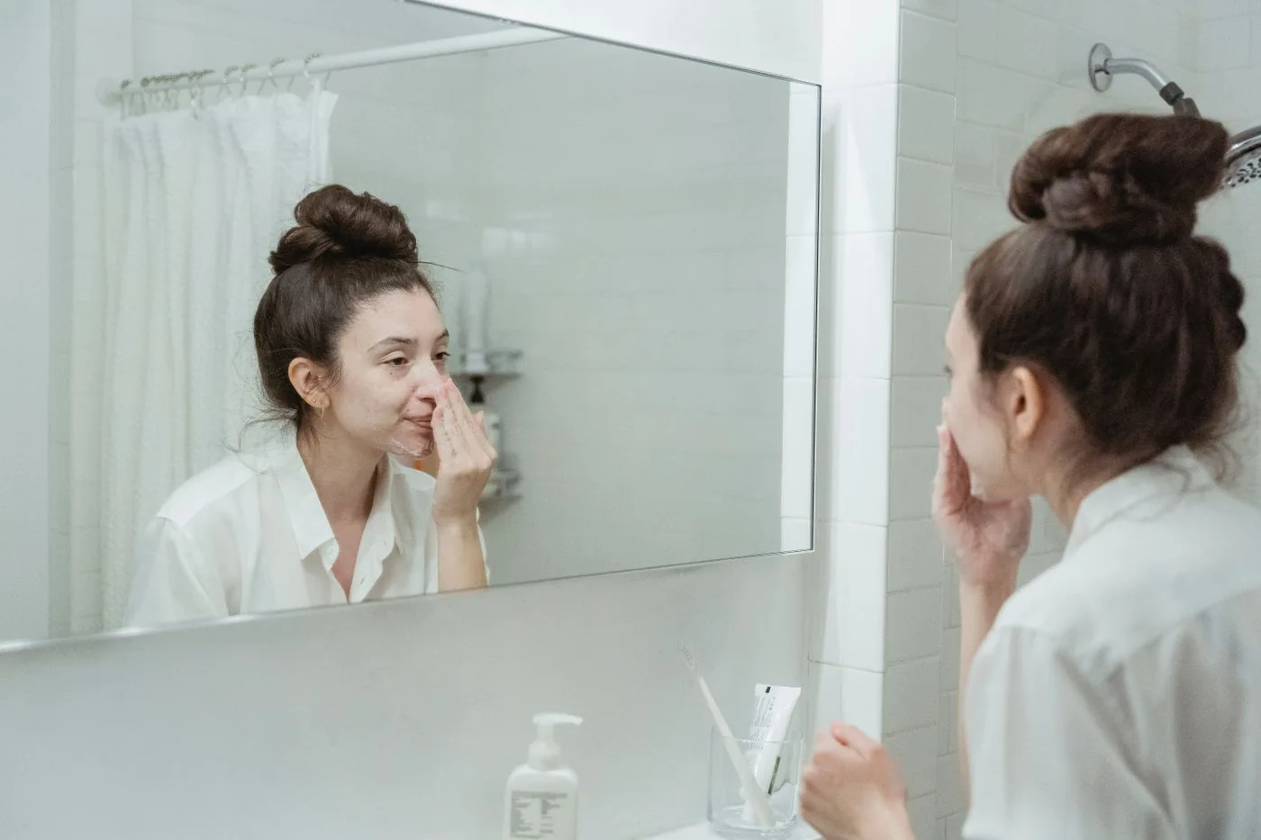 Woman applying skincare while looking in a bathroom mirror